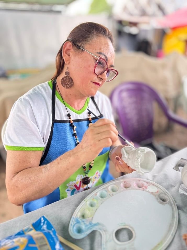 Artesã de avental pintando uma garrafa reaproveitada