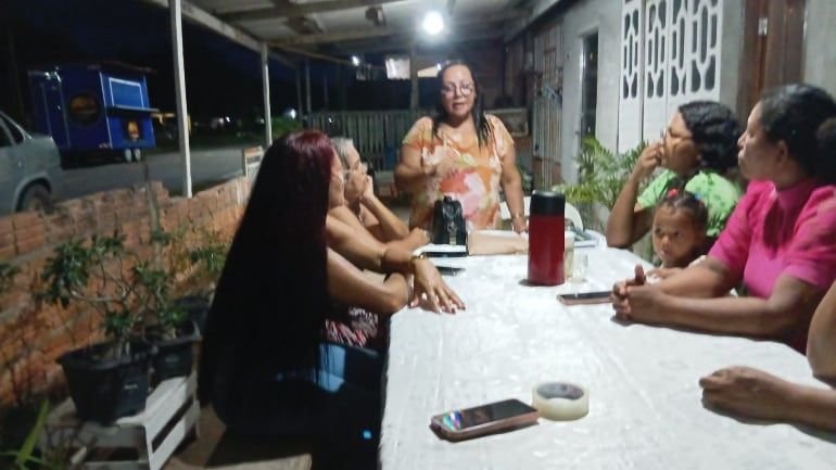 Mulheres sentadas à mesa numa varanda, à noite