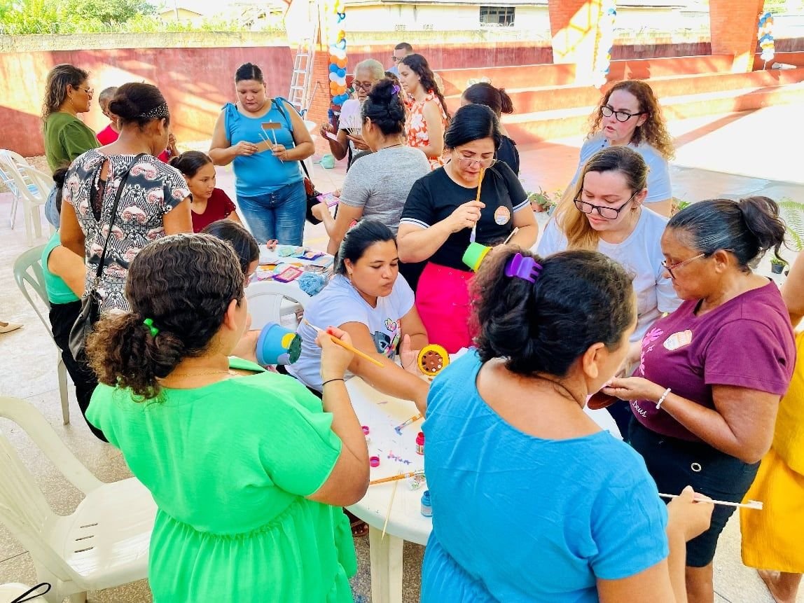 Mulheres trabalhando juntas em mesas de artesanato