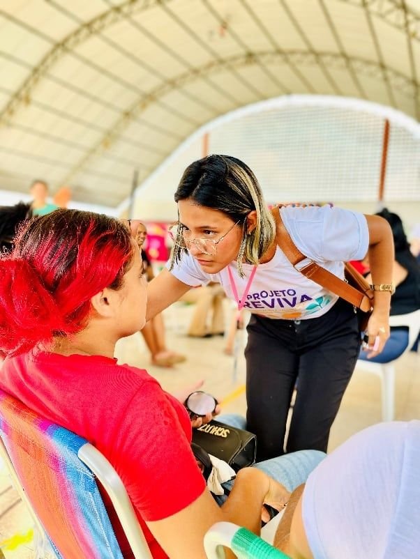 Mulher maquiando uma participante de cabelo vermelho