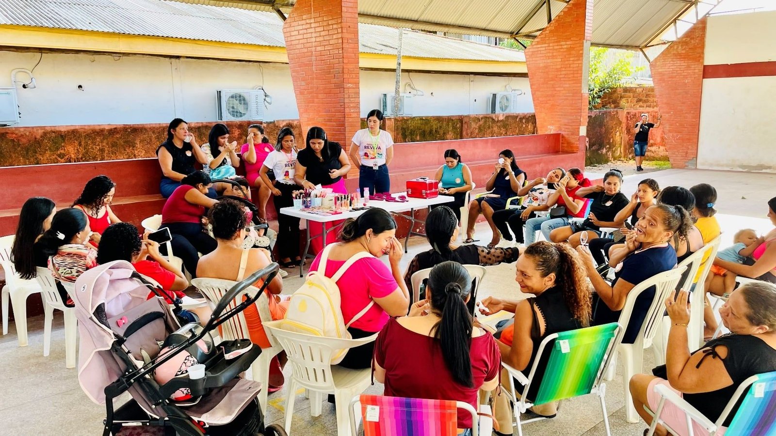 Grande grupo de mulheres sentadas em roda num pavilhão