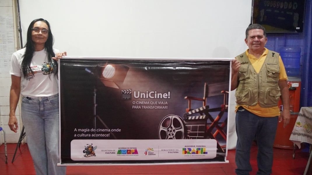 Duas pessoas segurando o banner do UniCine