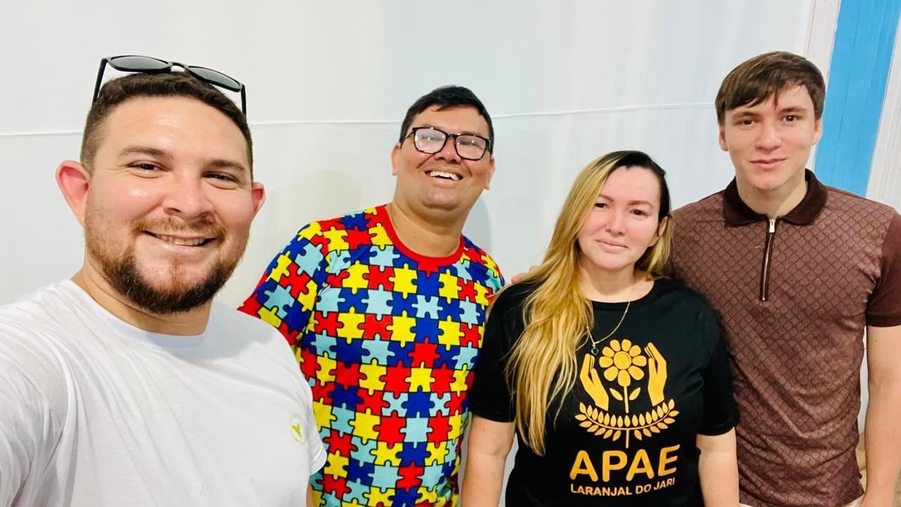 Quatro pessoas sorrindo para uma selfie, uma delas com camiseta da APAE