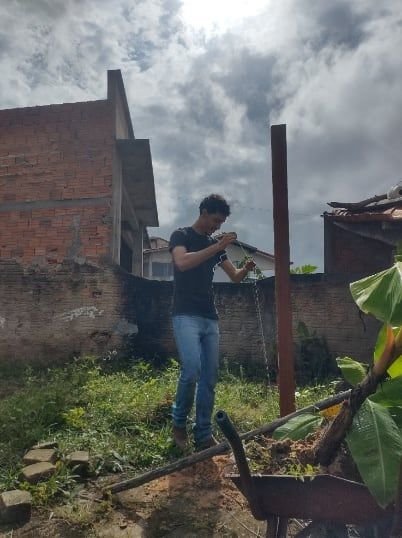 Pessoa trabalhando no alto de uma estrutura, sob céu nublado