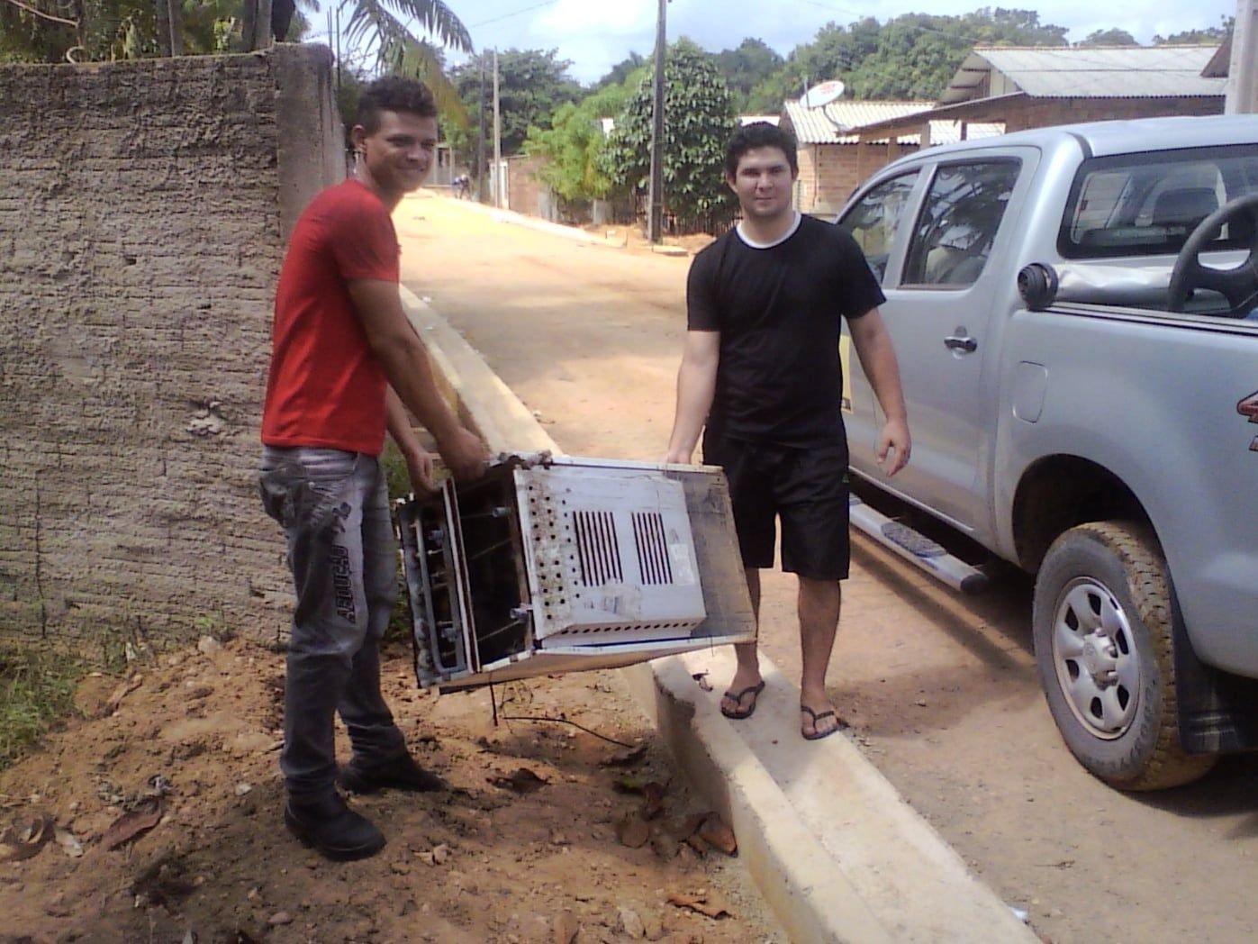 Dois homens carregando uma estante usada perto de uma caminhonete