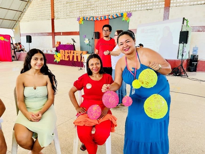 Três mulheres sentadas segurando bolas de artesanato amarelas